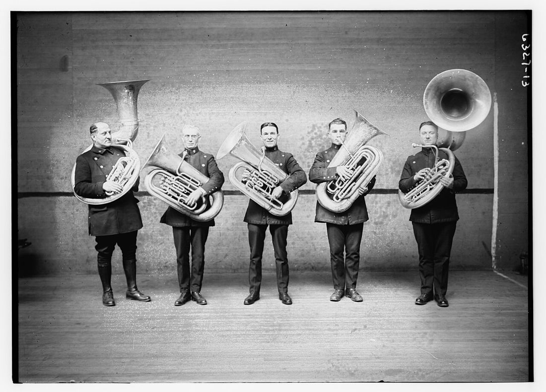 Five uniformed band members holding tubas and a sousaphone