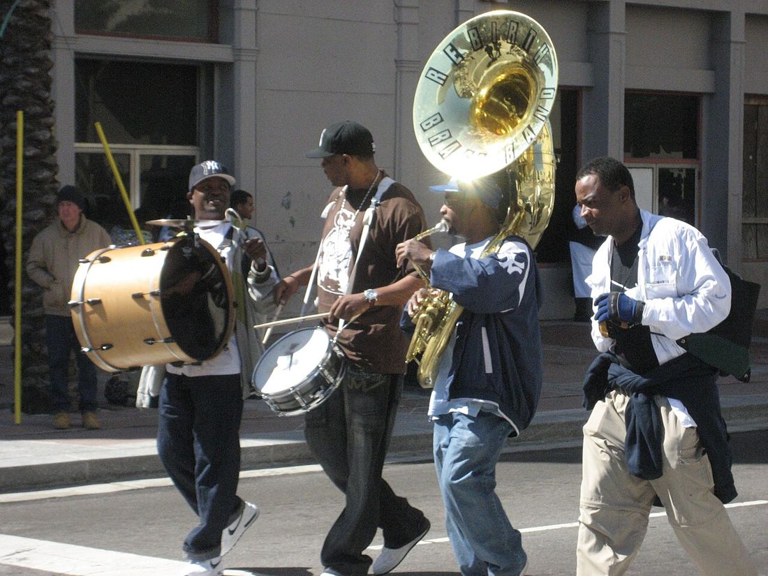 Rebirth Brass Band marching in a New Orleans street, with a sousaphone